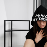 A woman in a hoodie with panic attack letters, representing mental health struggles.